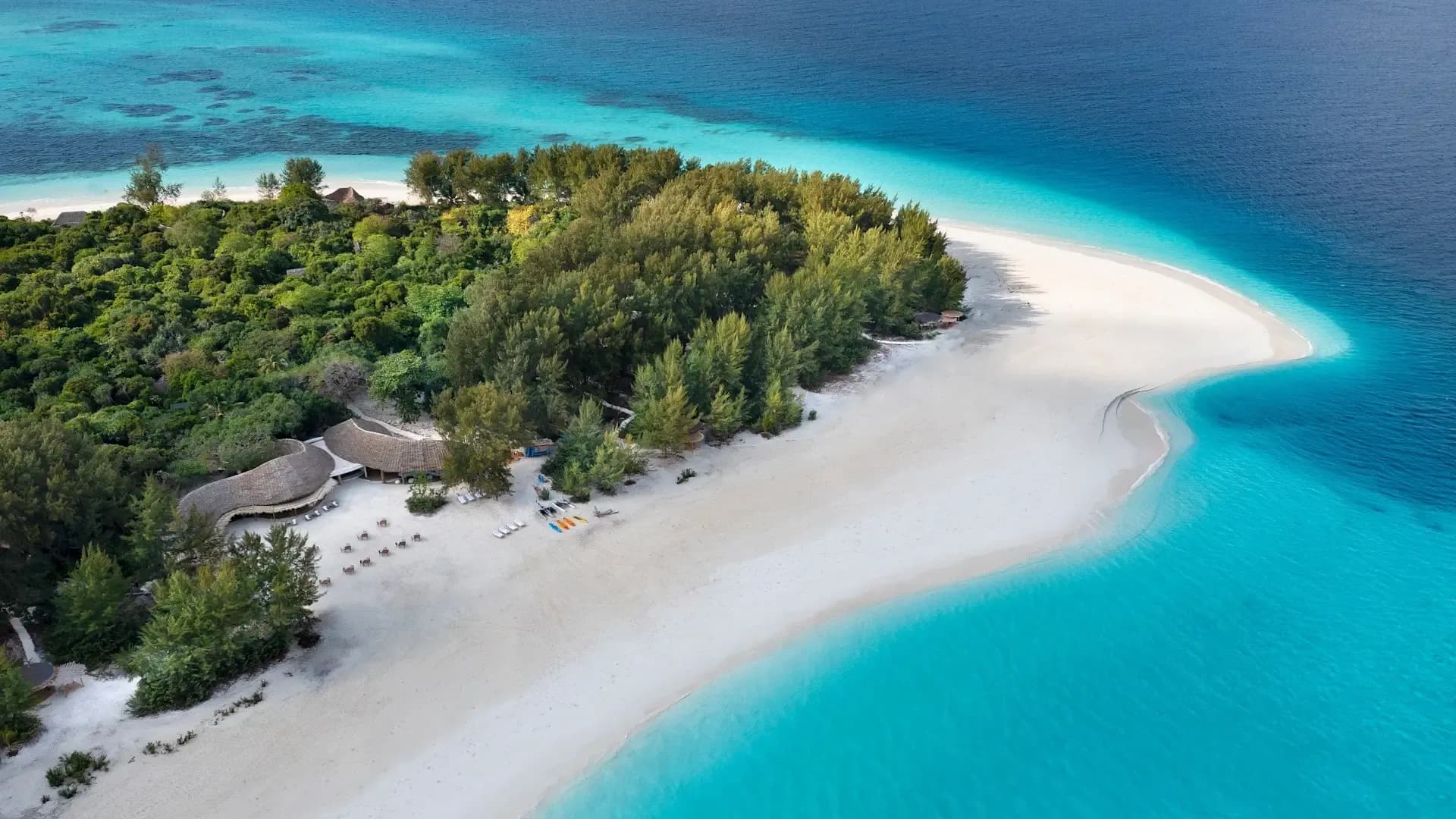 Aerial view of a small tropical island with a curving white sand spit and turquoise water, Mnemba Island, Zanzibar