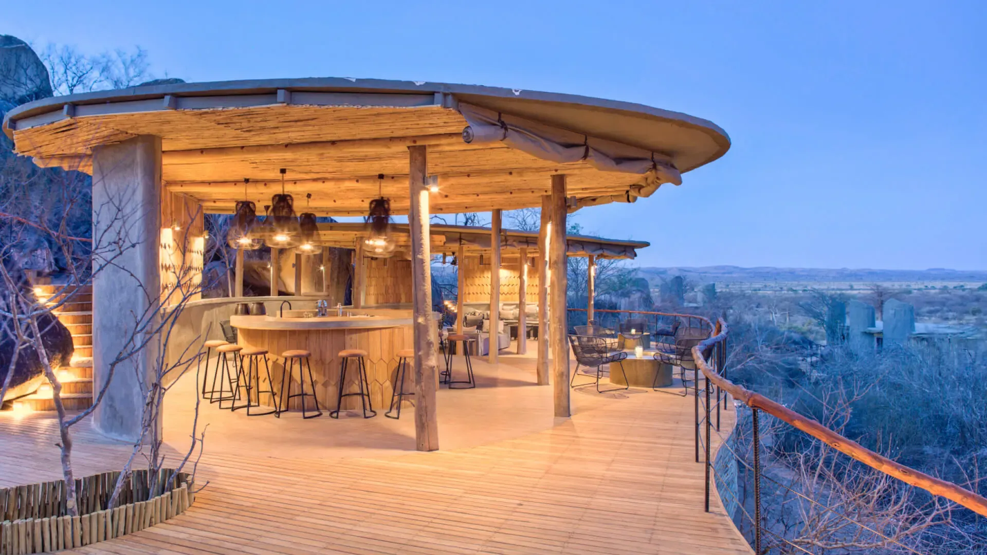 A timber bar and open deck beneath a thatched roof, built among granite boulders above the Ruaha plains, Jabali Ridge